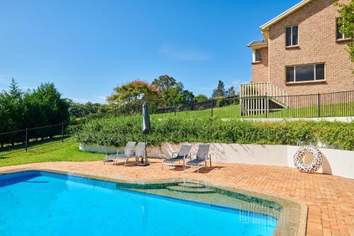 a swimming pool with chairs and a house at Ocean Views on Acres - Diamond Beach in Diamond Beach
