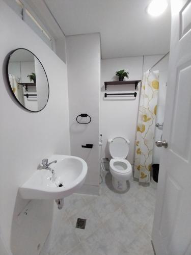 a white bathroom with a sink and a toilet at Bayay ni Lola in Mactan Cebu International