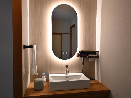 a bathroom with a sink and a mirror at Komakusa Hotel in Matsumoto