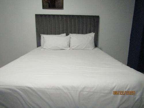 a large white bed with white sheets and pillows at The PHOMOLONG GUEST HOUSE in Roodepoort
