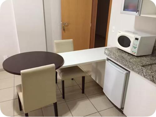 a kitchen with a table and a microwave at Águas da Serra - melhor hotel de Rio Quente in Rio Quente
