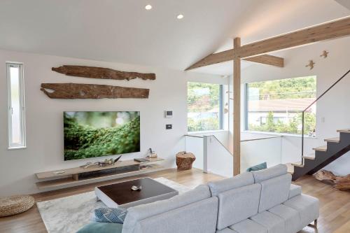 a living room with a couch and a tv on a wall at KeiU-Yakushima Guest House in Yakushima