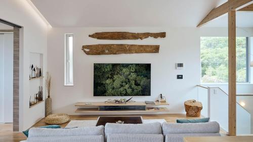 a living room with a couch and a tv on a wall at KeiU-Yakushima Guest House in Yakushima