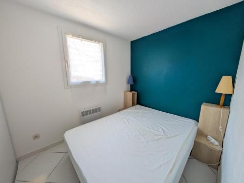 - une chambre avec un lit blanc et un mur bleu dans l'établissement Villa T3 Mezzanine à Port-la-Nouvelle: 6 pers, Terrasse, Proche Plage et Commerces, Confort Optimal. - FR-1-797-52, à Port-la-Nouvelle