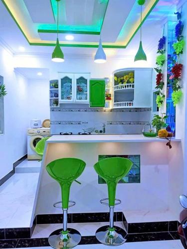 a kitchen with a bar with green stools at Hoàng Nga 2 Homestay in Phan Thiet