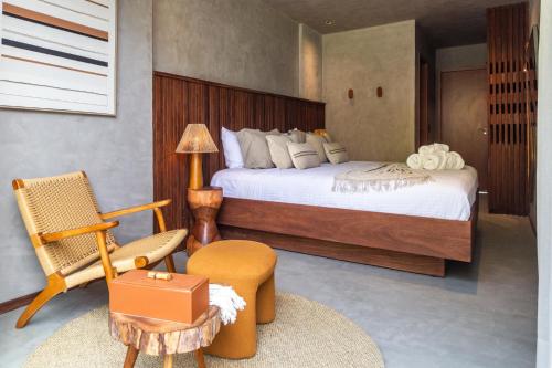 a bedroom with a large bed and a chair at Casa Bangalô dos Milagres in Passo de Camarajibe