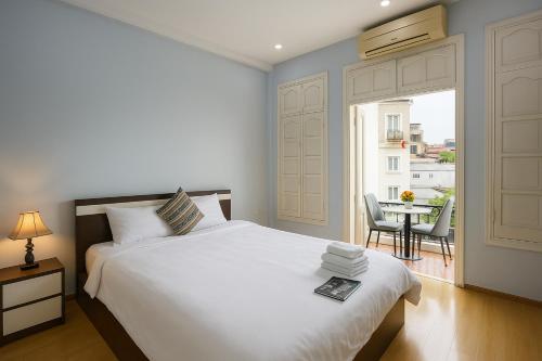 a bedroom with a bed and a balcony with a table at Eco Nest Hotel Đình Ngang in Hanoi