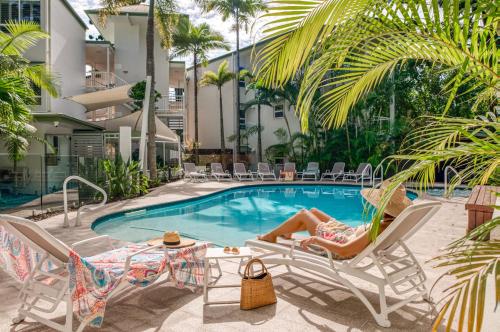 a woman laying in lawn chairs next to a swimming pool at The Lookout Resort Noosa in Noosa Heads