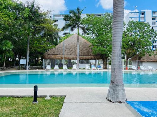 a swimming pool with a straw umbrella and a palm tree at Lovely 2 bedroom 2 bathroom condo in Cancún