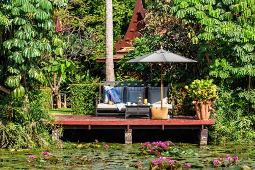 a patio with an umbrella and chairs next to a pond at Anantara Hua Hin Resort in Hua Hin