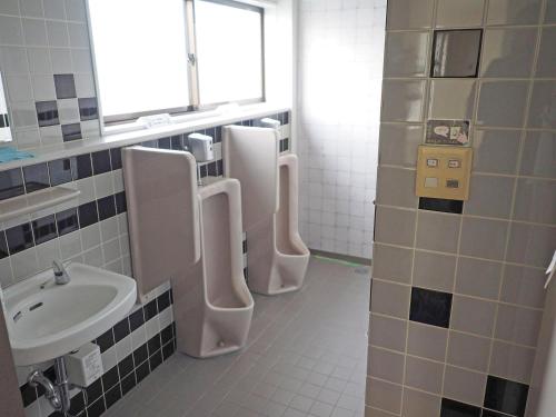 a bathroom with three urinals and a sink at マーケットステイ新宮 in Shingu