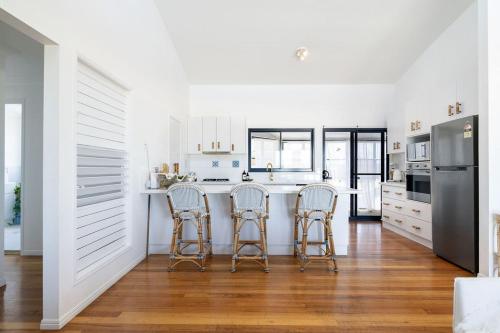 a kitchen with three bar stools and a refrigerator at Pacific House in Lennox Head