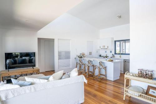 a white living room with a couch and a kitchen at Pacific House in Lennox Head