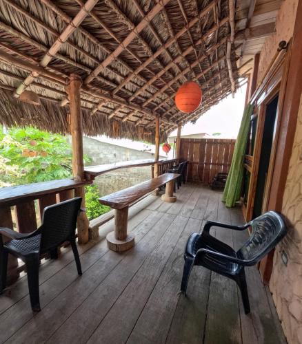 a porch with chairs and a table and a bench at Mi Cabaña El Maderal in Capurganá