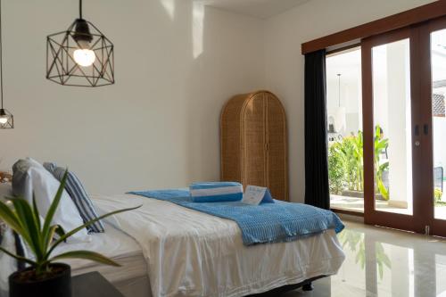 Un dormitorio con una cama y una planta en maceta. en Villa Azula Bali, en Canggu