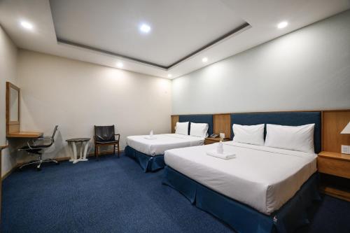 a hotel room with two beds and a desk at Sunshine Airport Hotel in Ho Chi Minh City