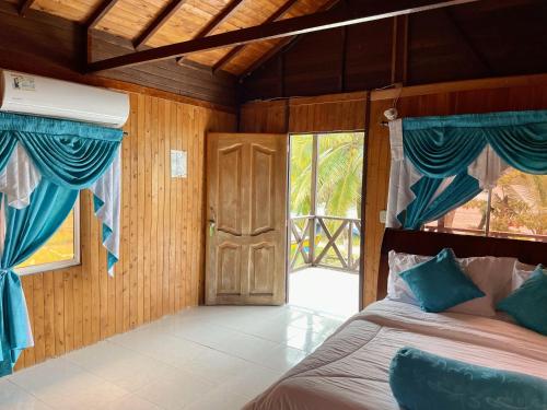 a bedroom with a bed with blue curtains and a door at Belcys House Sapzurro in Sapzurro