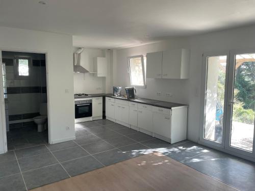 une cuisine avec des armoires blanches et un comptoir dans l'établissement Le Chêne Doré, à Villelongue-dʼAude