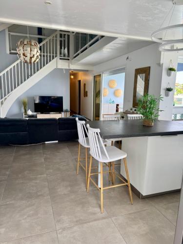 a kitchen and living room with a counter and chairs at Villa Téloam- Charmante villa avec piscine et vue mer in Schœlcher