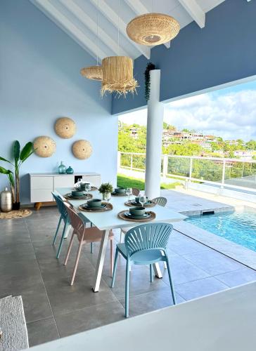 a dining room with a table and chairs and a pool at Villa Téloam- Charmante villa avec piscine et vue mer in Schœlcher