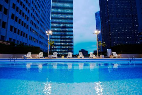 a large swimming pool with chairs and a city skyline at Keio Plaza Hotel Tokyo Premier Grand in Tokyo