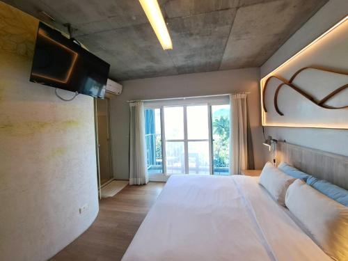 a bedroom with a large white bed and a window at 墾丁橘月Orange Moon Inn in Kenting