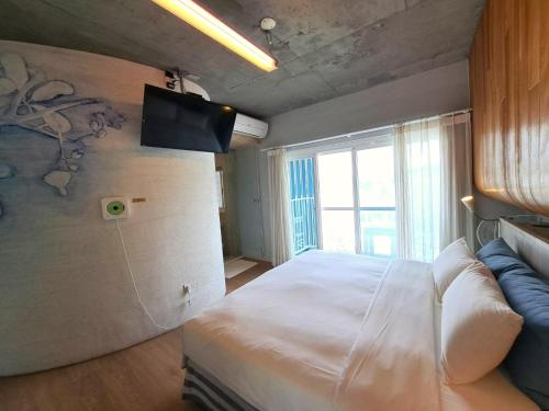 a bedroom with a bed and a tv on the wall at 墾丁橘月Orange Moon Inn in Kenting