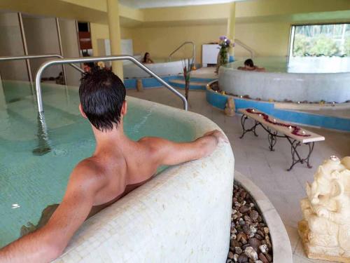 a young man in a bath tub in a swimming pool at Villa immersed in the pine forest in Sardinia in Arborea 