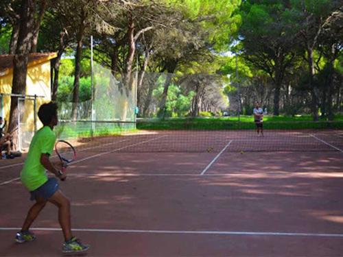 two people playing tennis on a tennis court at Villa immersed in the pine forest in Sardinia in Arborea 