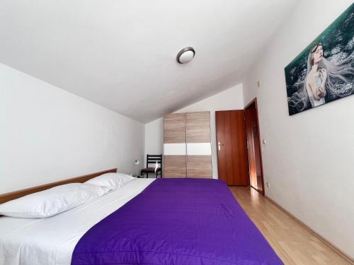 a bedroom with a large bed with purple sheets at Apartment Danijela in Vodice