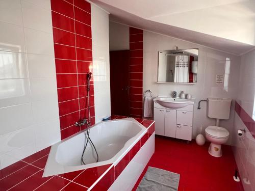 a red and white bathroom with a tub and a toilet at Apartment Danijela in Vodice