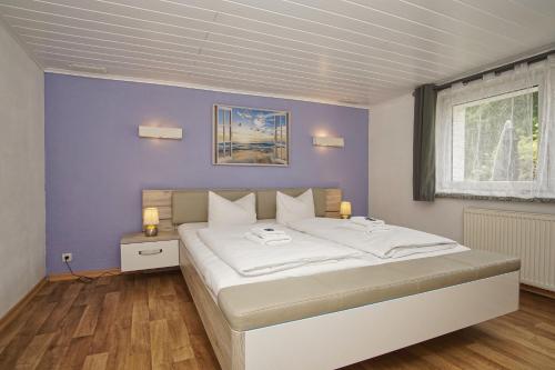 a bedroom with a large white bed with purple walls at Ferienhus Baabe bei Familie Vergien in Baabe