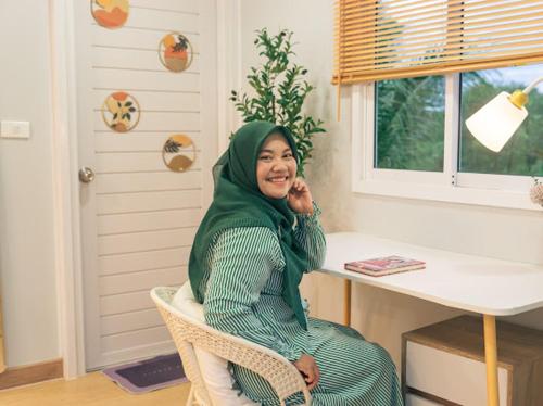 a woman sitting in a chair in front of a desk at Cana Garden Minimal 4 in Satun
