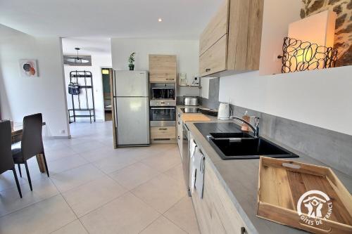 a kitchen with a sink and a refrigerator at Le ptit bois rolland in Plancoët
