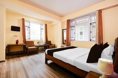 a bedroom with a bed and a desk and windows at Hotel O De Sikkim Regency in Gangtok