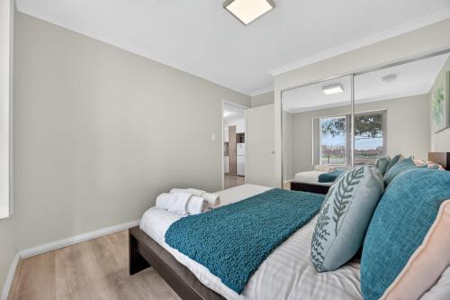 a bedroom with a large bed with blue pillows at Stylish Corporate Stay with Wi-Fi & Parking in Rockingham