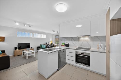 a kitchen with white cabinets and a living room at Stylish Corporate Stay with Wi-Fi & Parking in Rockingham
