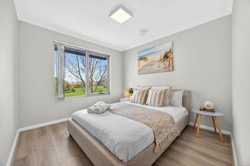 a white bedroom with a bed and a window at Stylish Corporate Stay with Wi-Fi & Parking in Rockingham