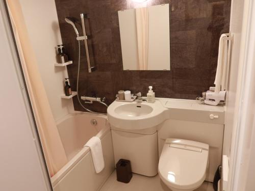 a bathroom with a sink and a toilet and a bath tub at Henn na Hotel Komatsu Ekimae in Komatsu