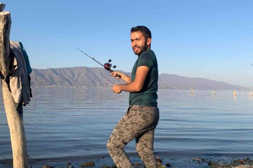 a man standing in the water holding a fishing rod at Casa de Campo Lake Shore Jocotepec in San Cristóbal Zapotitlán