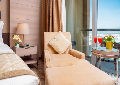 a hotel room with a bed and a chair and a window at Fashion Avenue Dubai Mall in Dubai