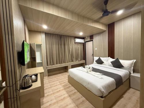 a bedroom with a large bed and a television at Hotel Alohi Grand in Guwahati