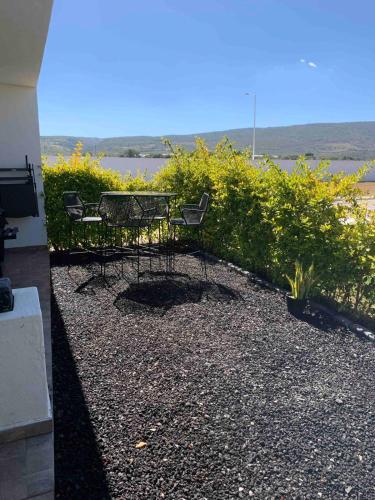 a patio with two chairs and a table and bushes at Casa de Campo Lake Shore Jocotepec in San Cristóbal Zapotitlán