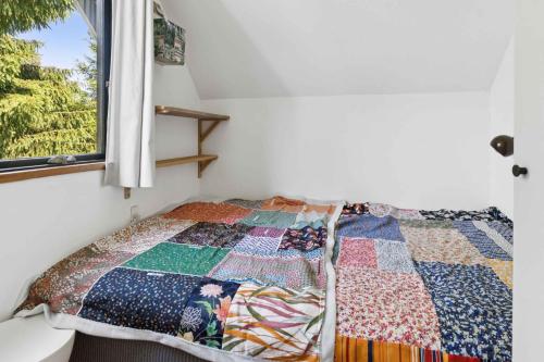a quilt on a bed in a room with a window at Scenic Cottage Within Walking Distance To Beach in Nakskov