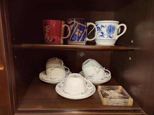 a shelf with cups and saucers in a cabinet at ゲストハウス長閑 in Toyooka