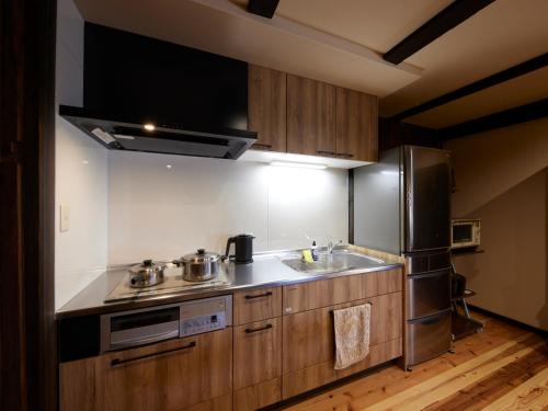 a kitchen with a sink and a refrigerator at ゲストハウス長閑 in Toyooka