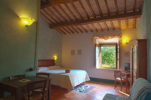 a bedroom with a bed and a table and a window at SARNA Residence in San Quirico dʼOrcia
