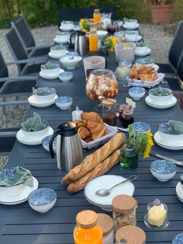 une longue table bleue avec des assiettes et des bols de nourriture dans l'établissement Maison etang, à Gien
