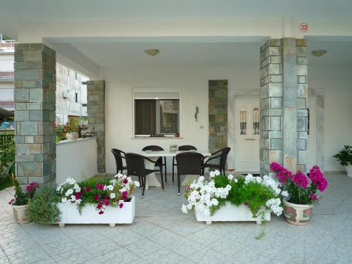 オリンピアキ・アクティにあるFrideriki Apartmentsの花の咲くパティオ(テーブル、椅子付)