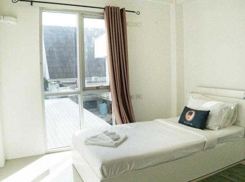 a white bedroom with a bed with a window at RQ Bangkok Sukhumvit 50 by Collection O in Amphoe Phra Khanong